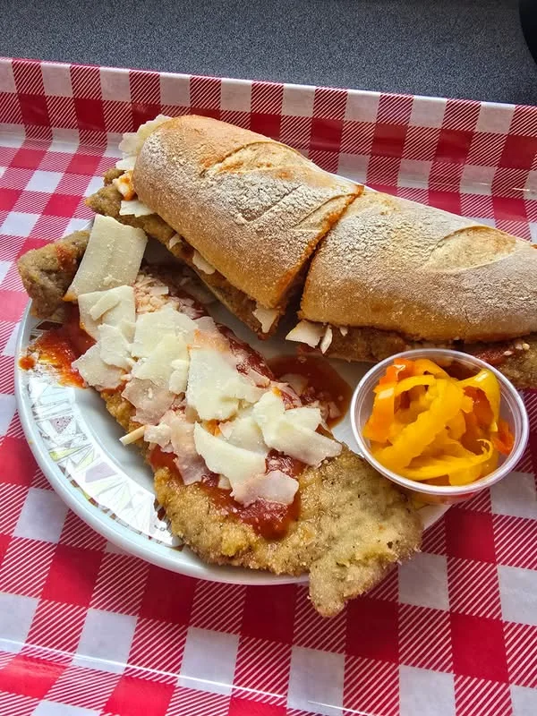 A breaded cutlet sandwich with tomato sauce and cheese