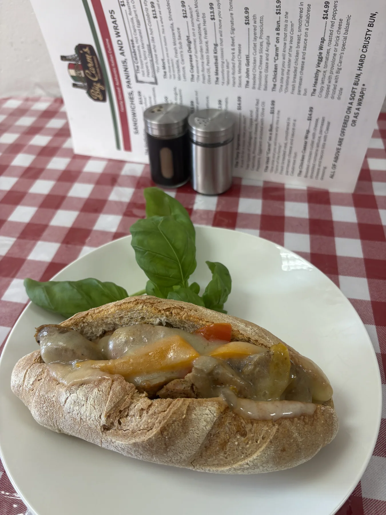 A Big Carm’s hot sandwich on a plate at a red-checkered market table